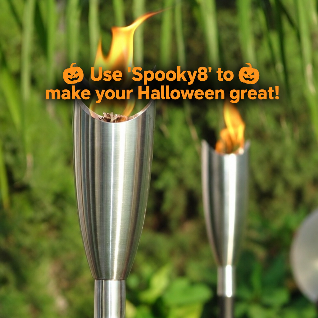 A stainless steel outdoor torch light with a flame, shown in front of a blurred green garden background. Orange text overlay reads: 'Use 'Spooky8' to make your Halloween great!' with pumpkin icons.