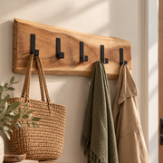 a rustic wooden coat rack with black metal hootks, on a hallway wall with bags and coats hanging off it
