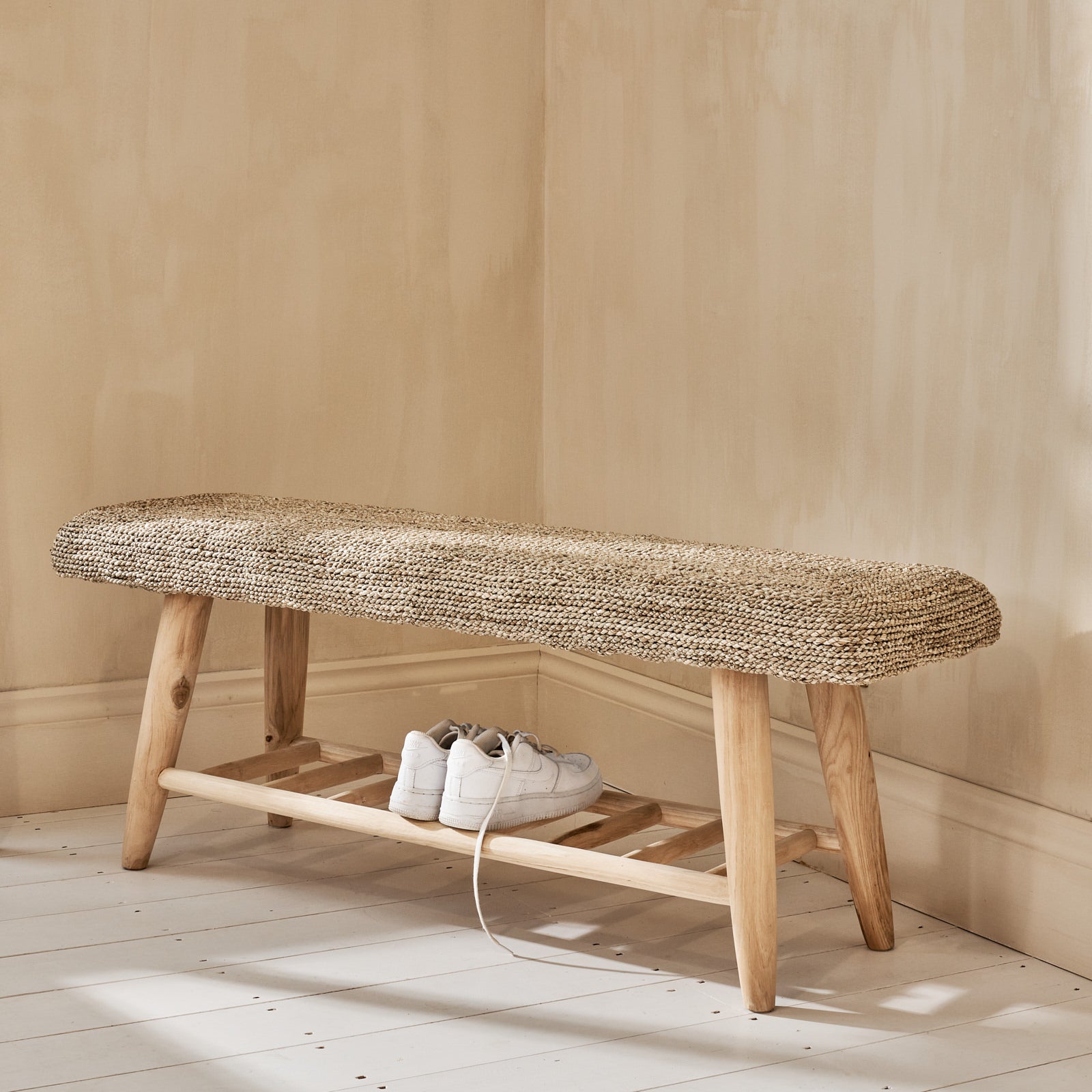 Seagrass wicker bench on wooden floor with shoes on shelf