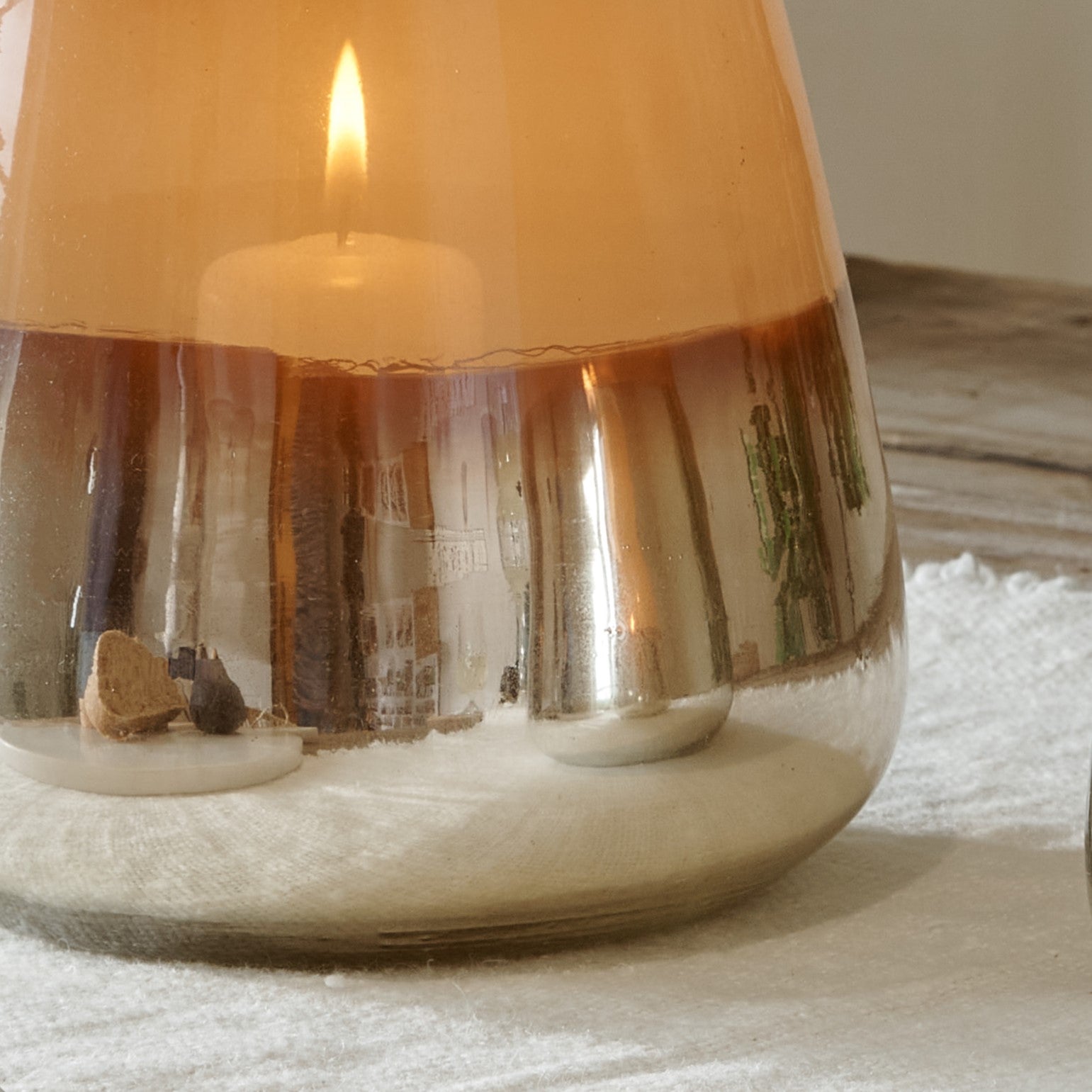 Close up of bottom of metallic hurricane lantern on cotton runner