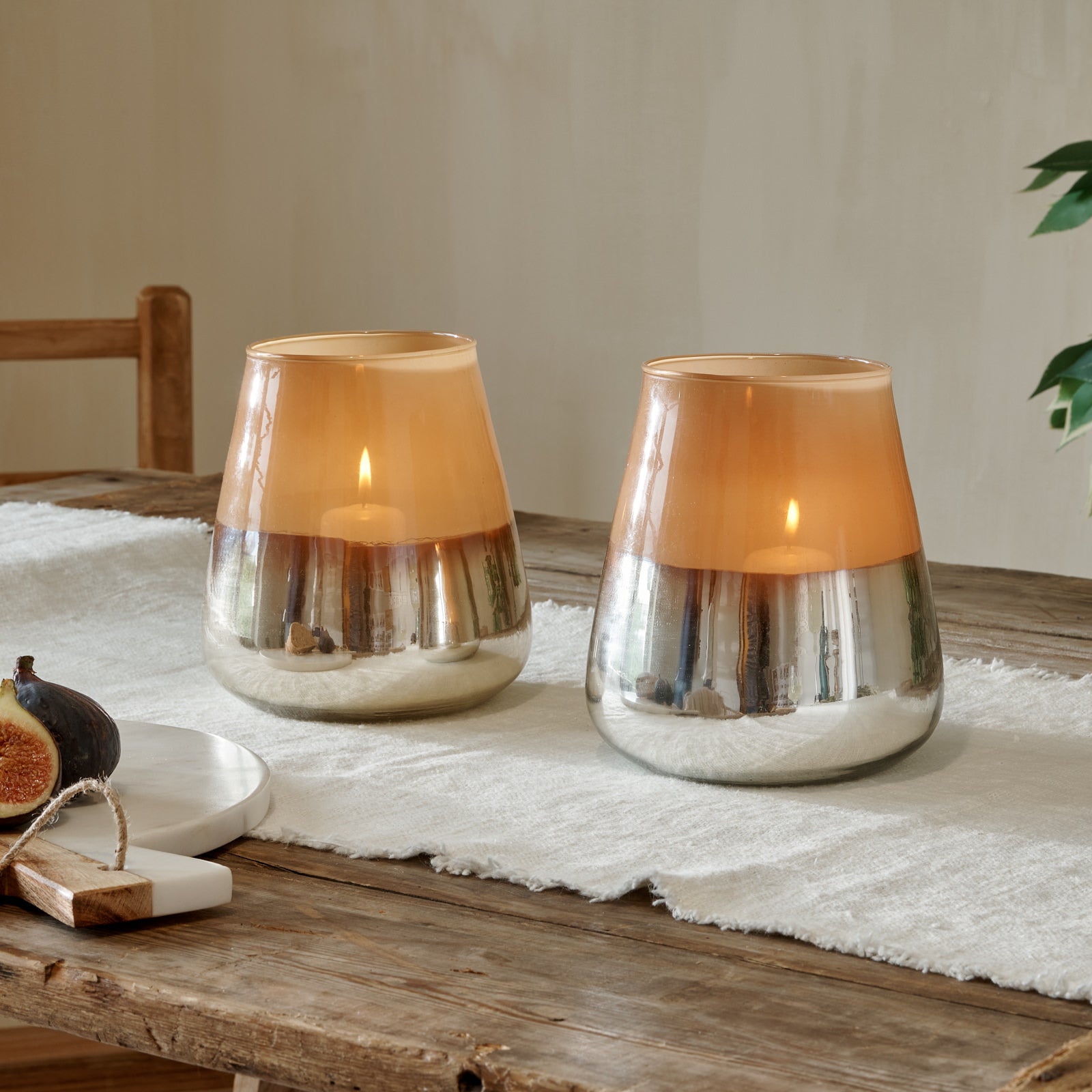 Tall indoor hurricane candle lamp metallic, on wooden table with cotton runner