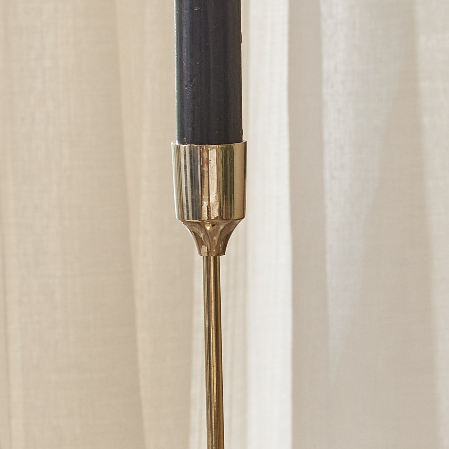 Close up of top of elegant gold candlestick with black candle