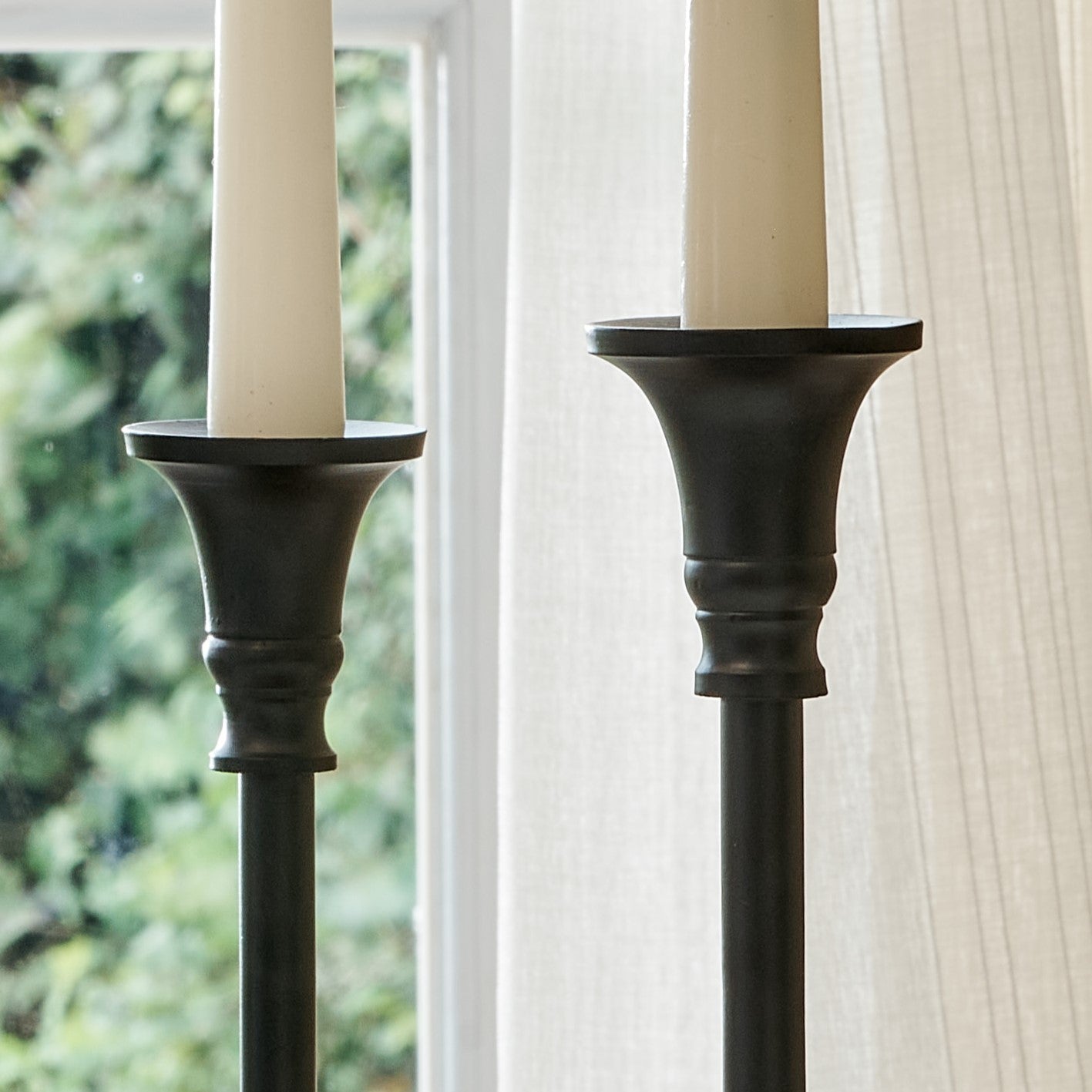 Close up of tops of elegant black candlesticks with white candles