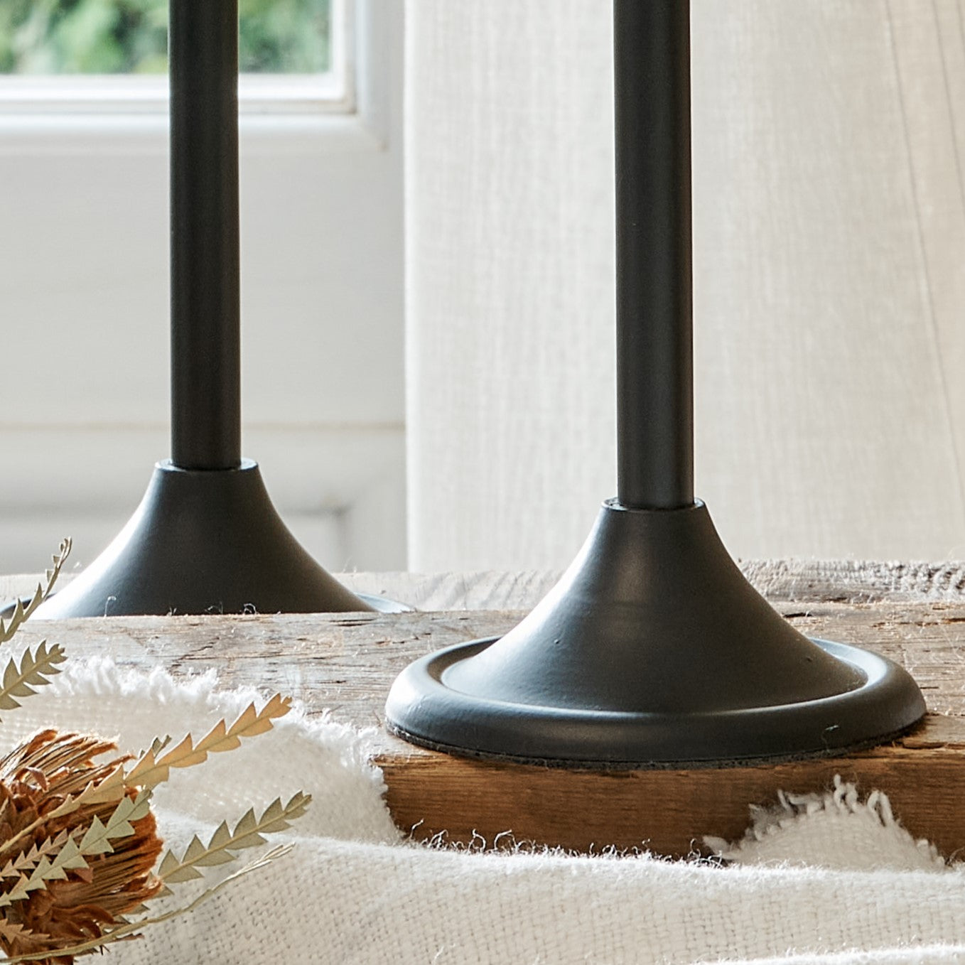 Close up of bases of elegant black candlesticks on wooden board