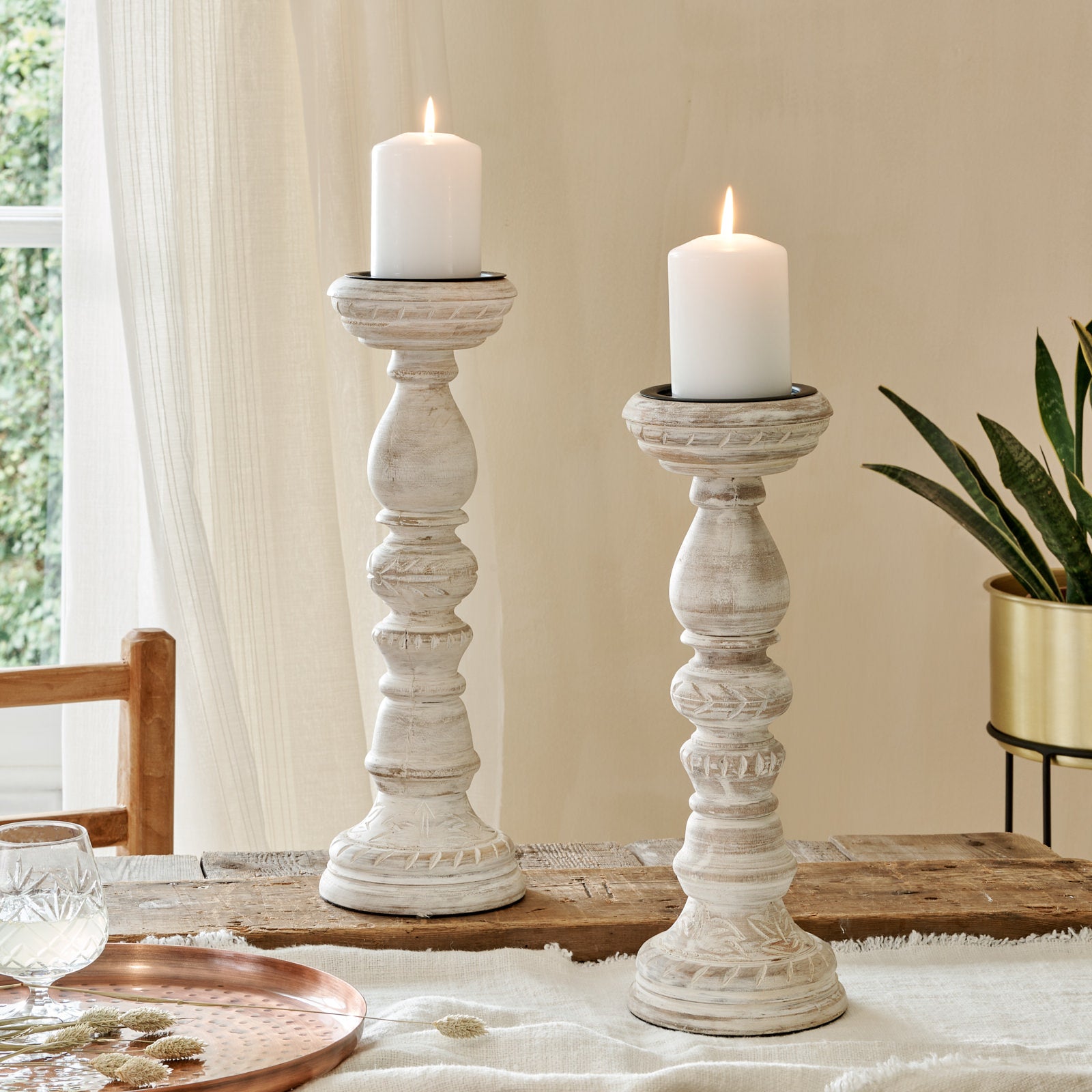 Large mango wood candle holders whitewash finish, on wooden table with cotton runner, with copper tray and planter
