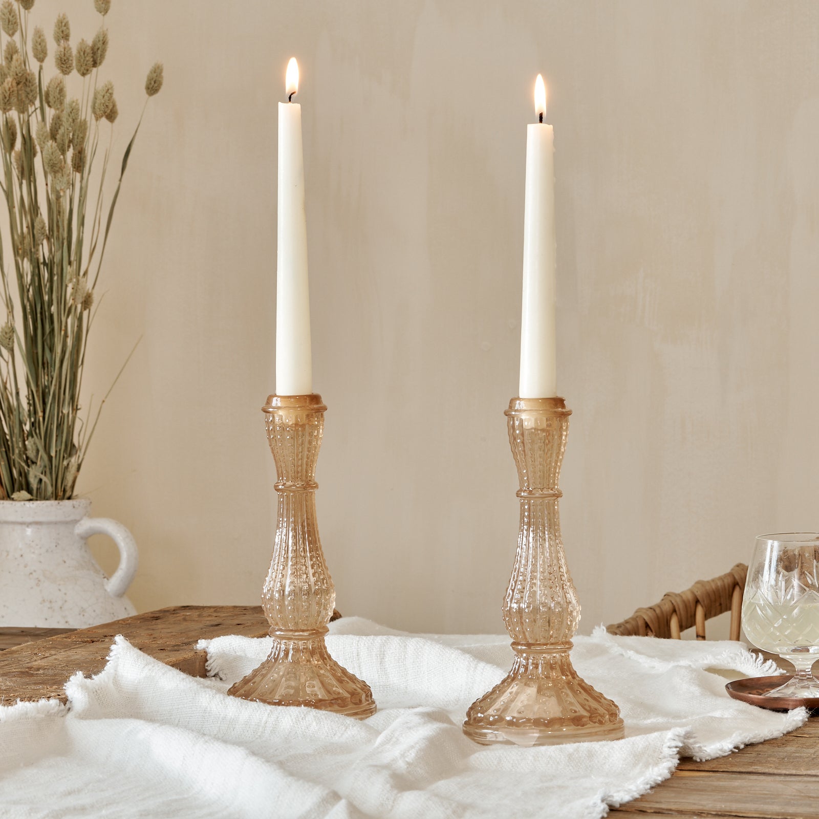Pink Glass Candlestick on cotton runner on wooden table