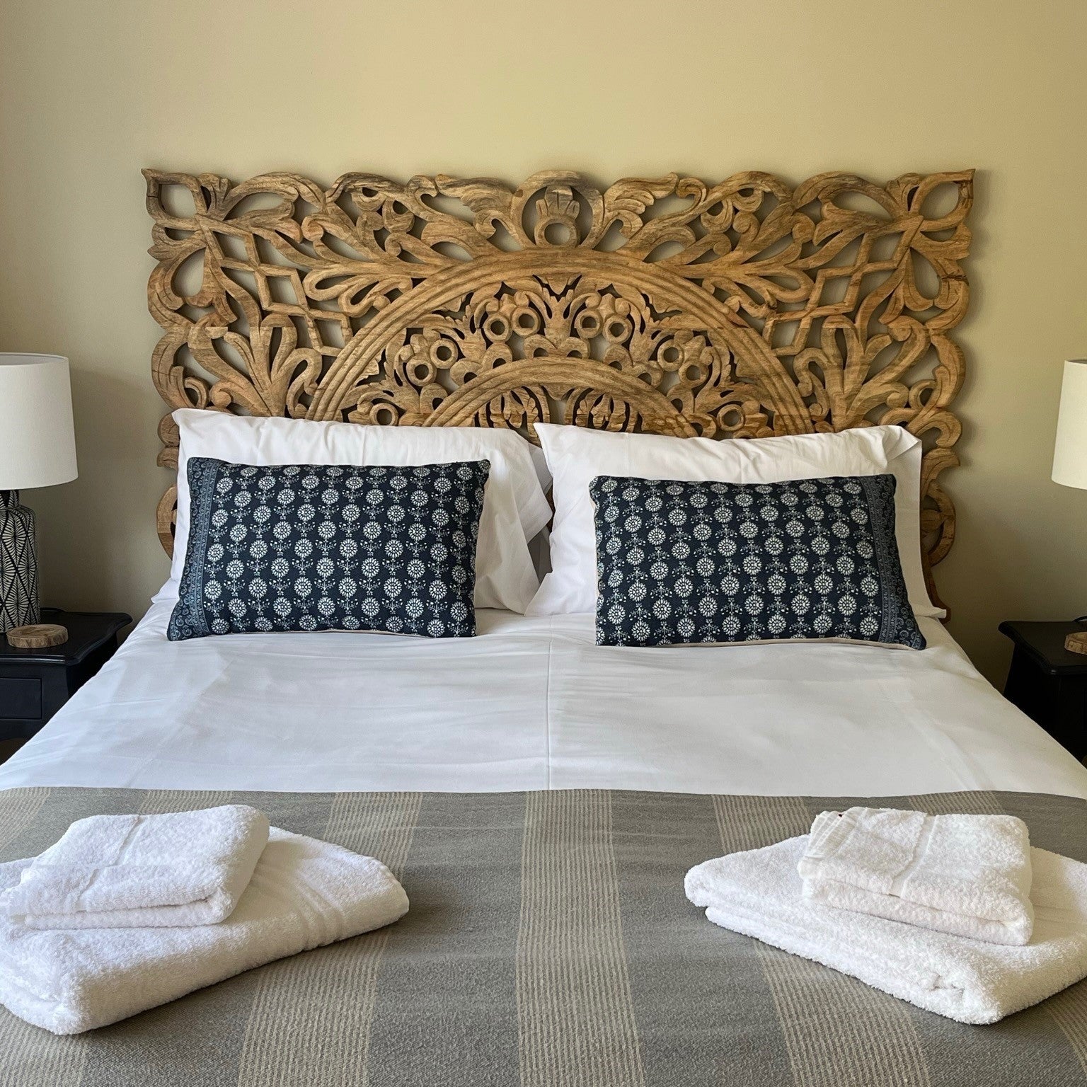 Carved Wooden Headboard on Bed with cushions and towels