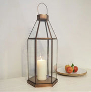 Hexagonal brass lantern on white table with bowl of fruit