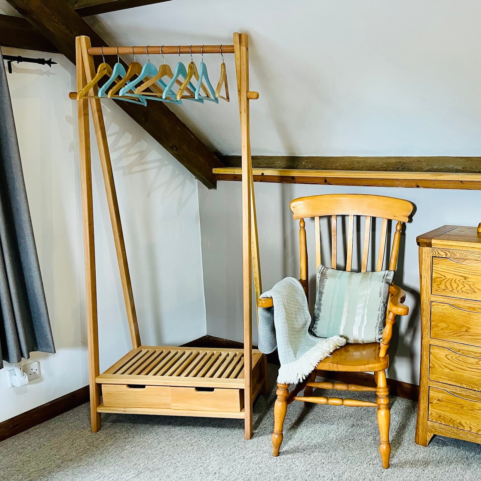 Wooden clothes rail in bedroom with chair and blanked