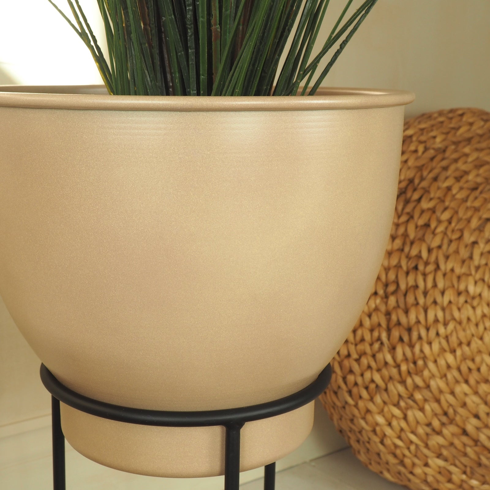 Close up photo of moroccan plant pot indoor with wicker pouffe in background