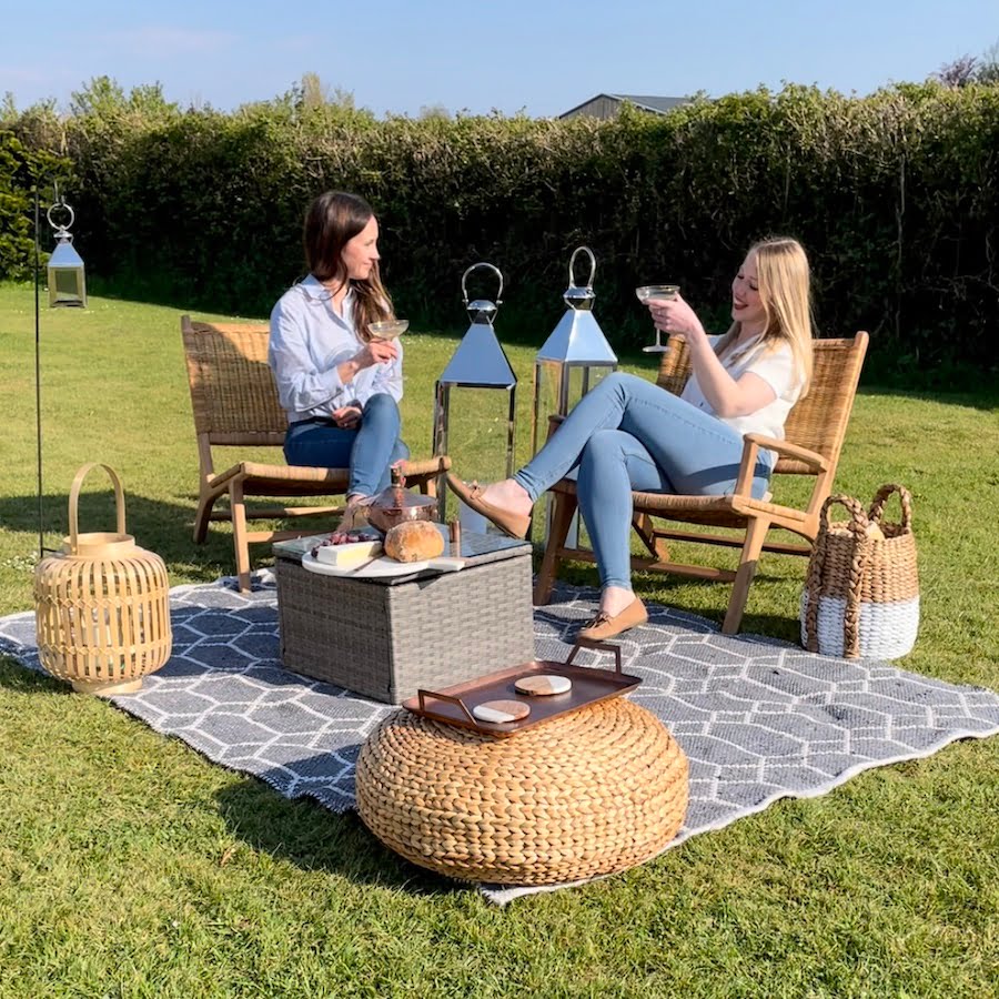 rattan garden chairs on rug with cushions,baskets and lanterns in the garden.