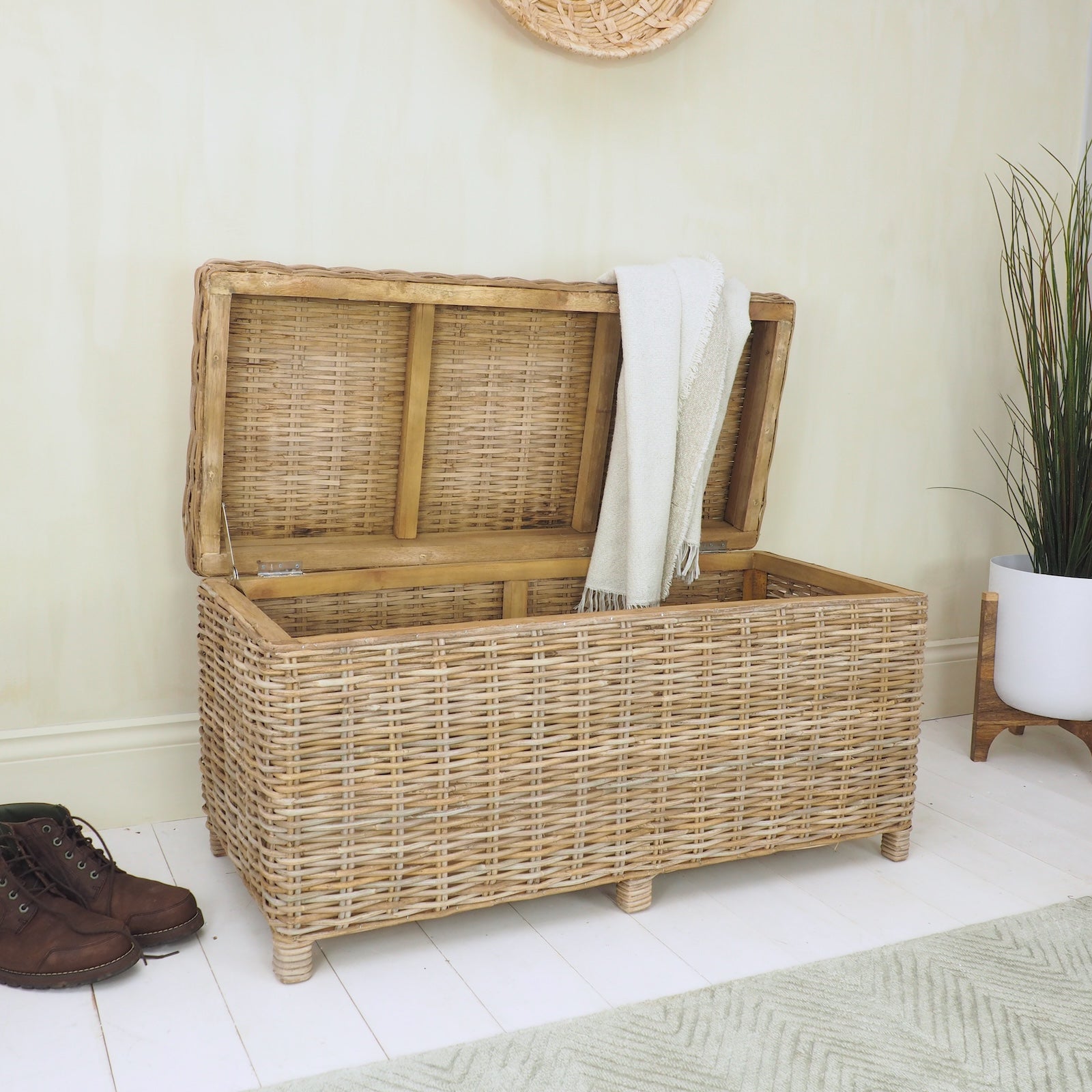 rattan storage trunk with open lid, plant in pot on white wooden floor