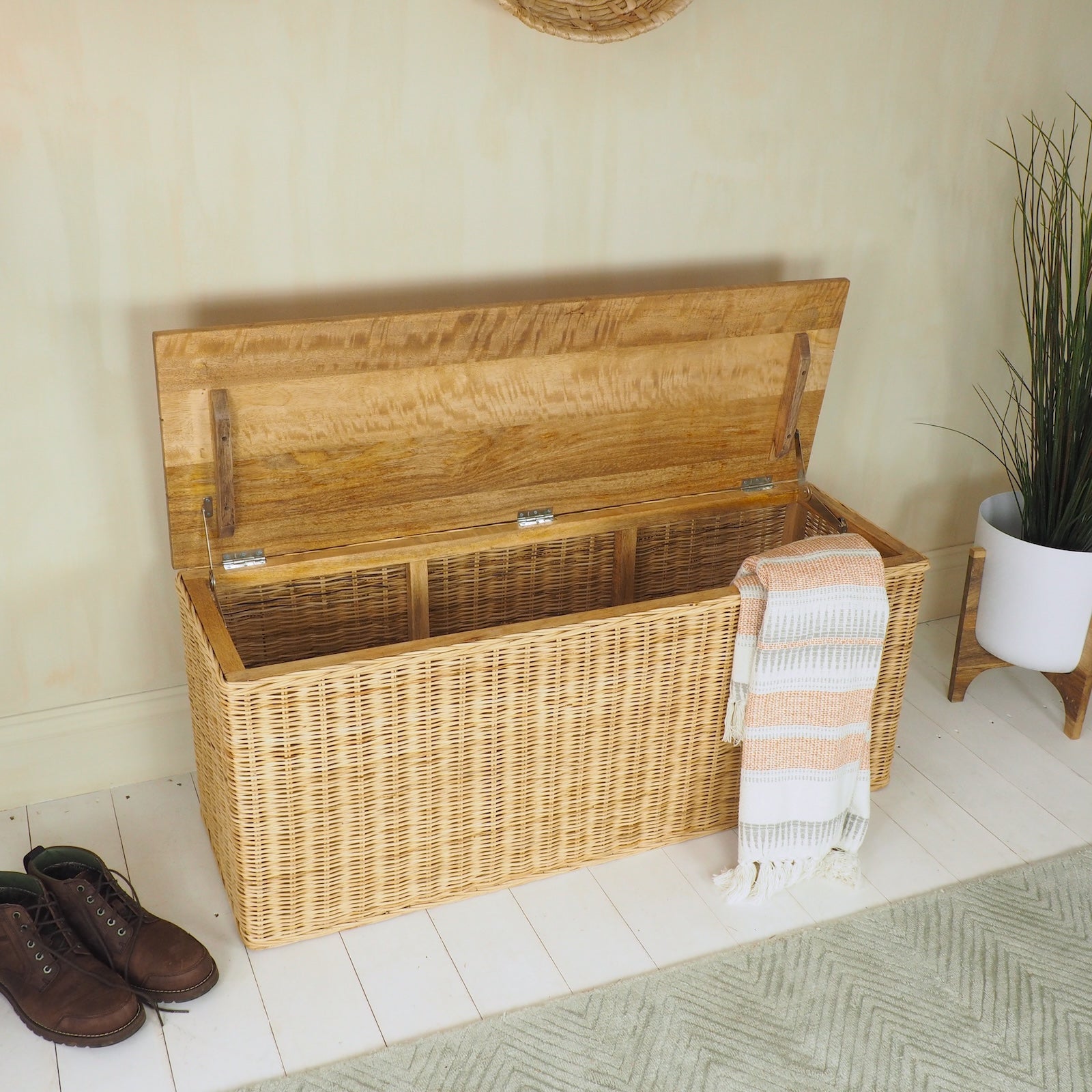 wicker storage bench with lid open, moroccan throw and green rug