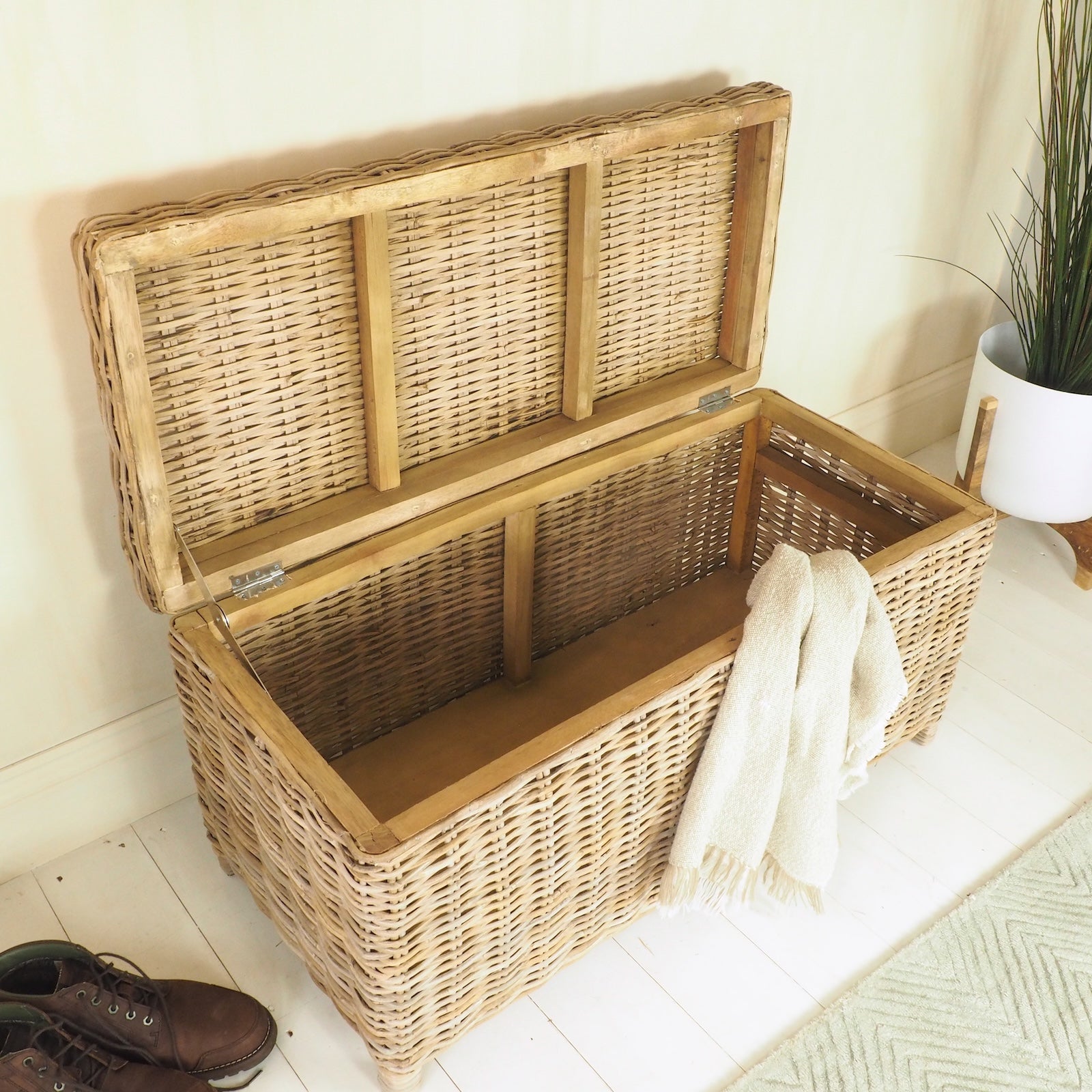wicker storage trunk with lid open, plant in pot and scarf