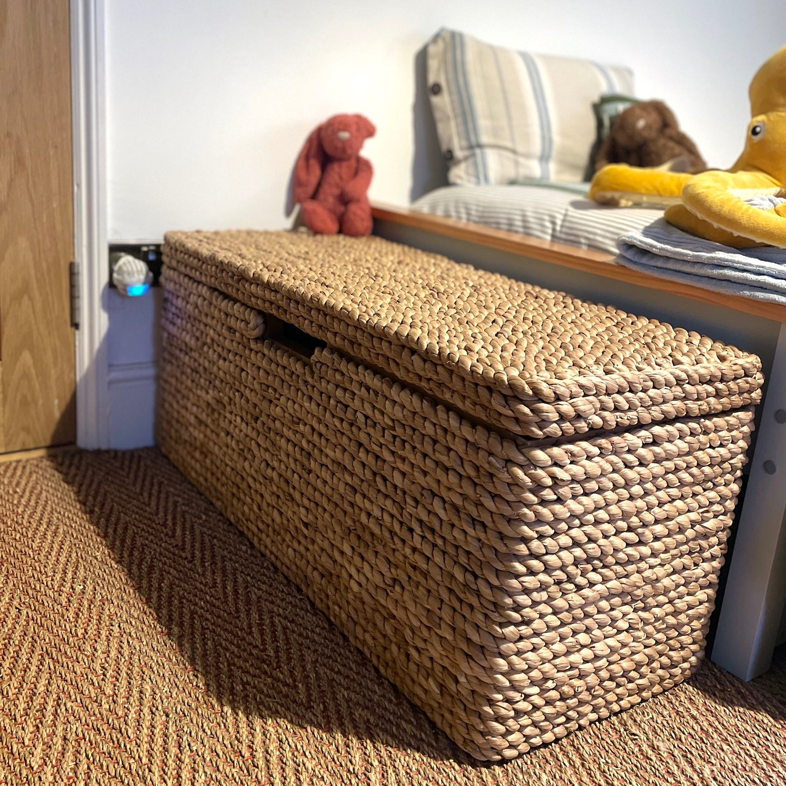 wicker storage trunk at end of child's bed