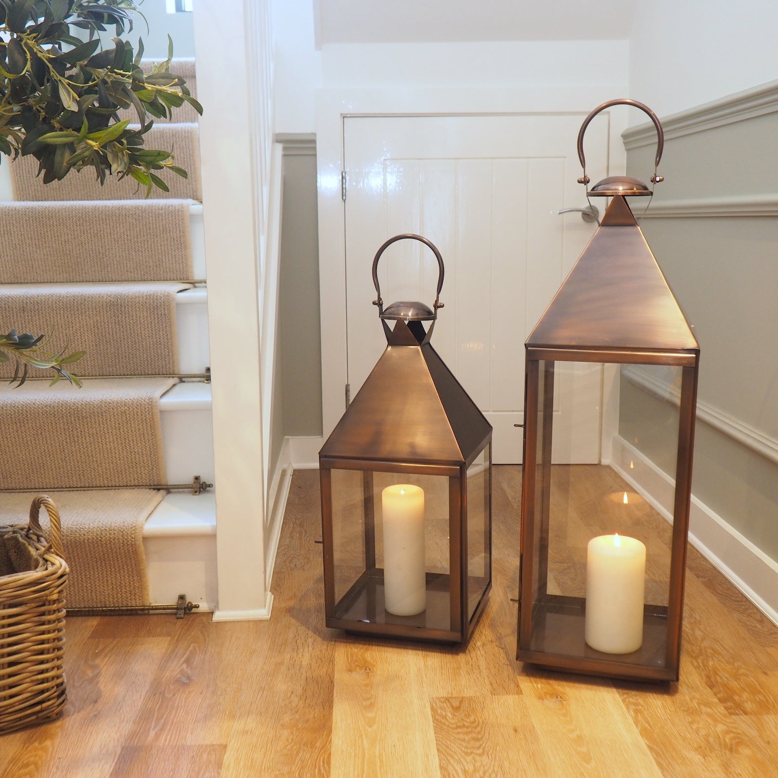 tall copper candle lanterns in hallway with staircase