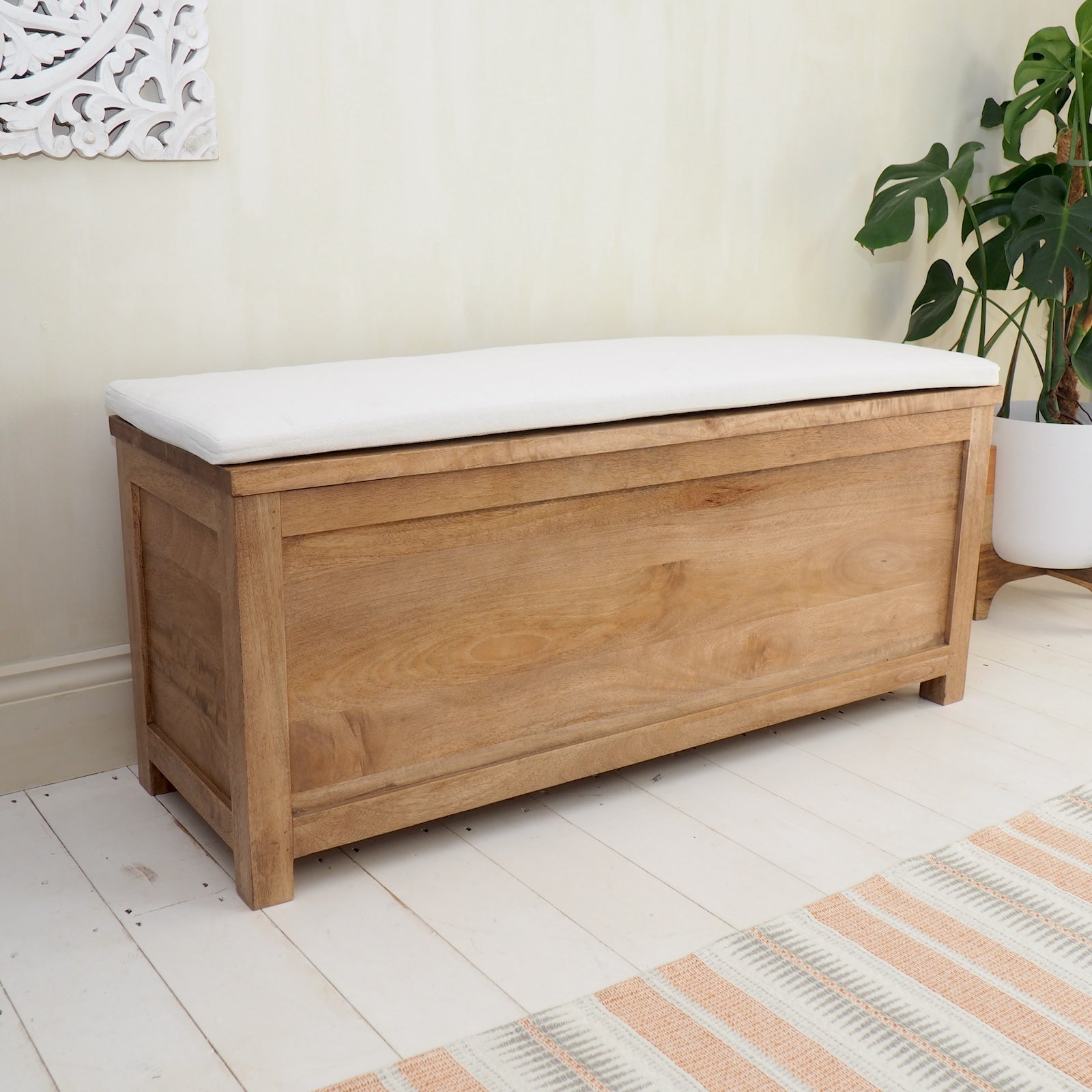 Wicker Storage Trunk with cushion o white wooden floor with striped rug
