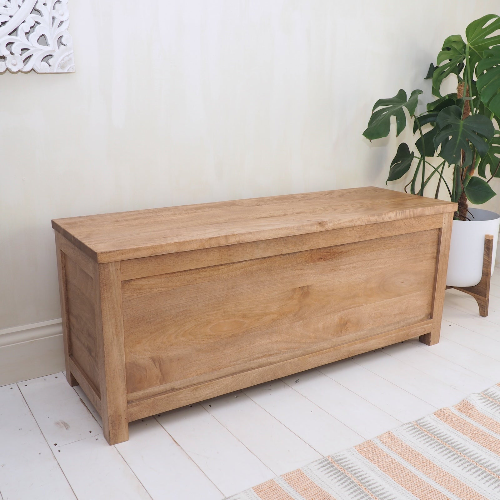 Wooden Storage Trunk with closed lid on white wood floor with plant and rug