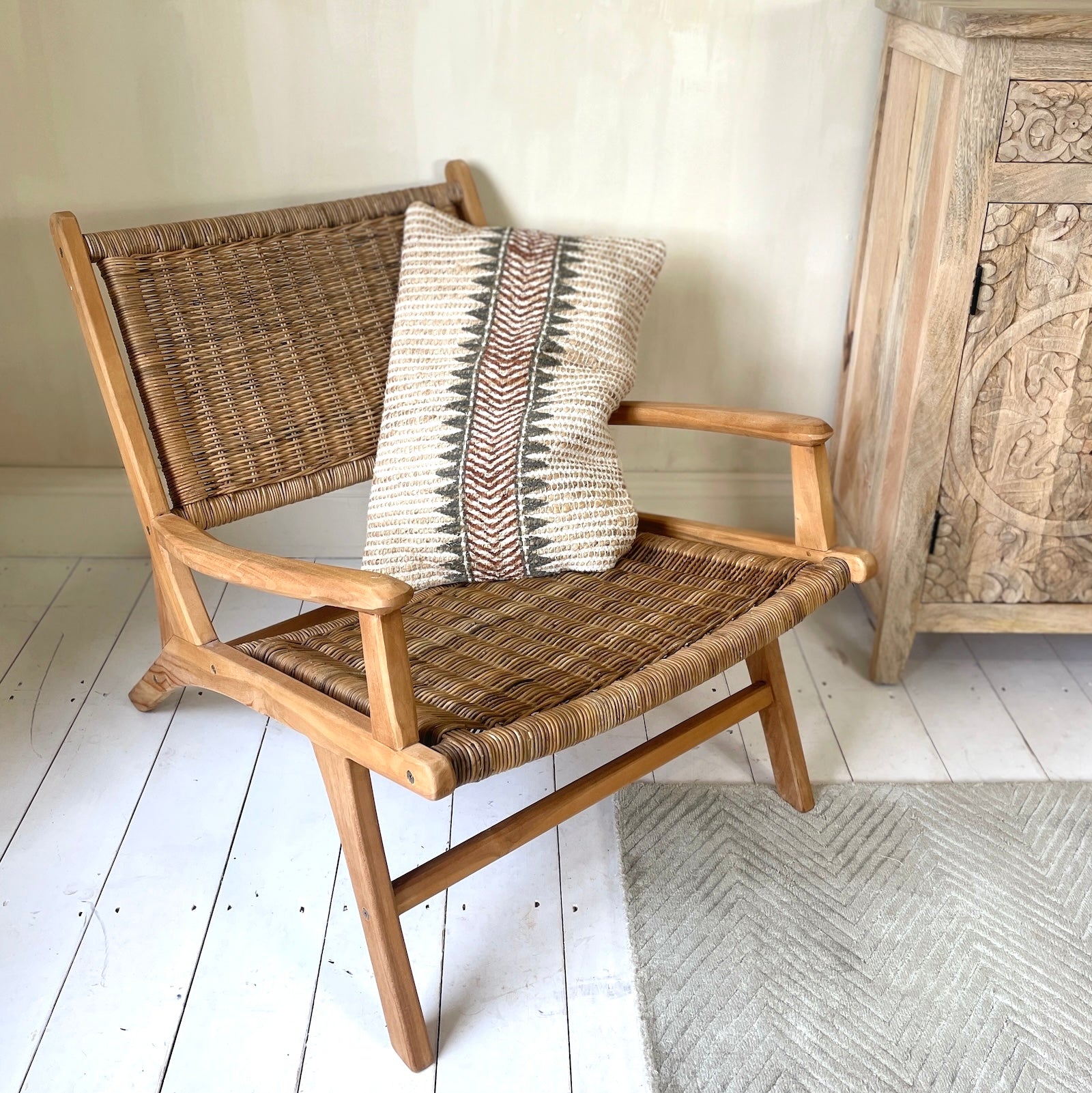 rattan arm chair in living room with green rug and wooden floors