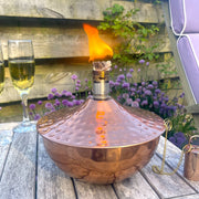 Copper outdoor citronella oil lantern in garden with drinks and nature