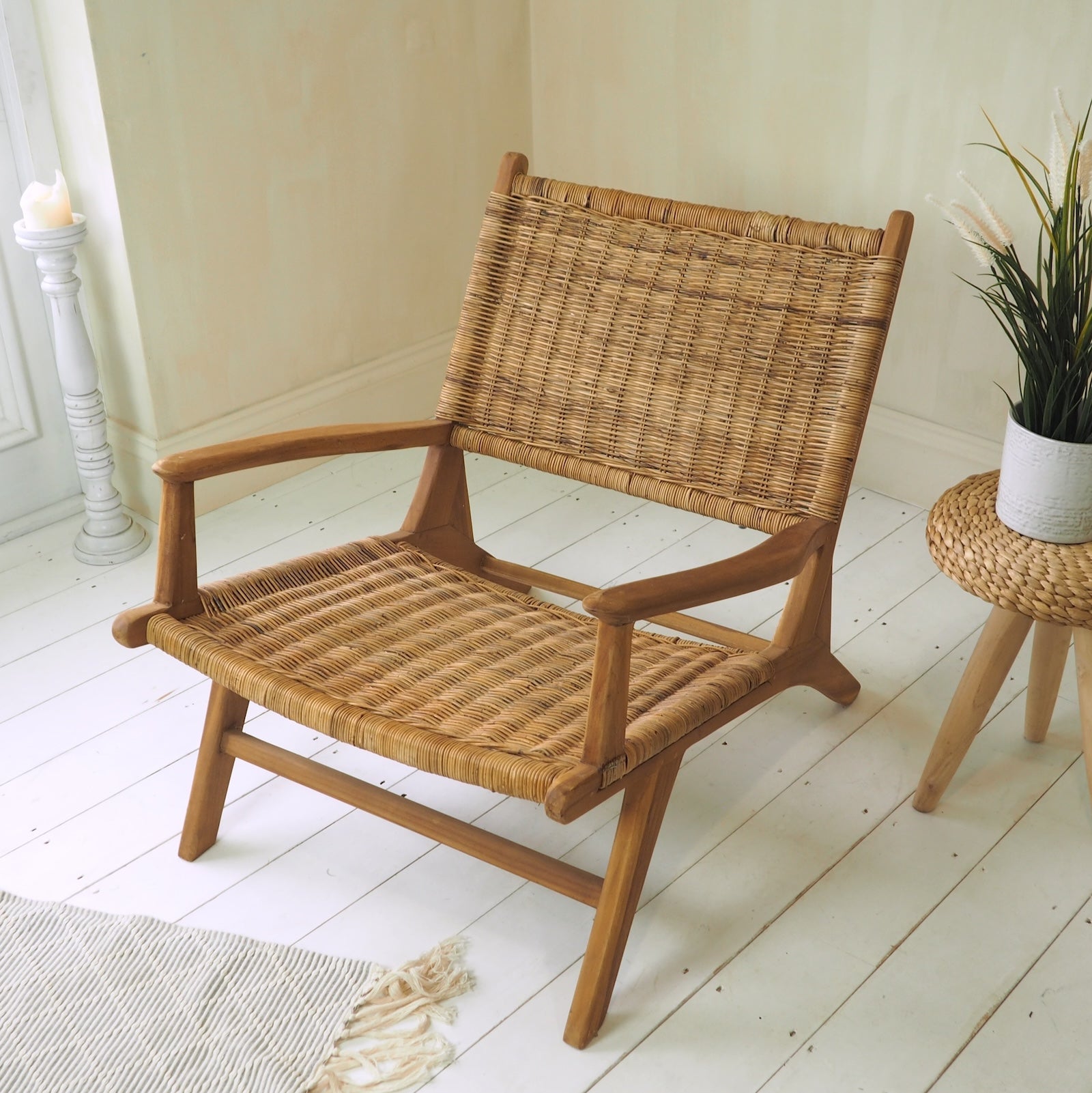 Rattan arm chair in conservatory with plant and white wooden floor