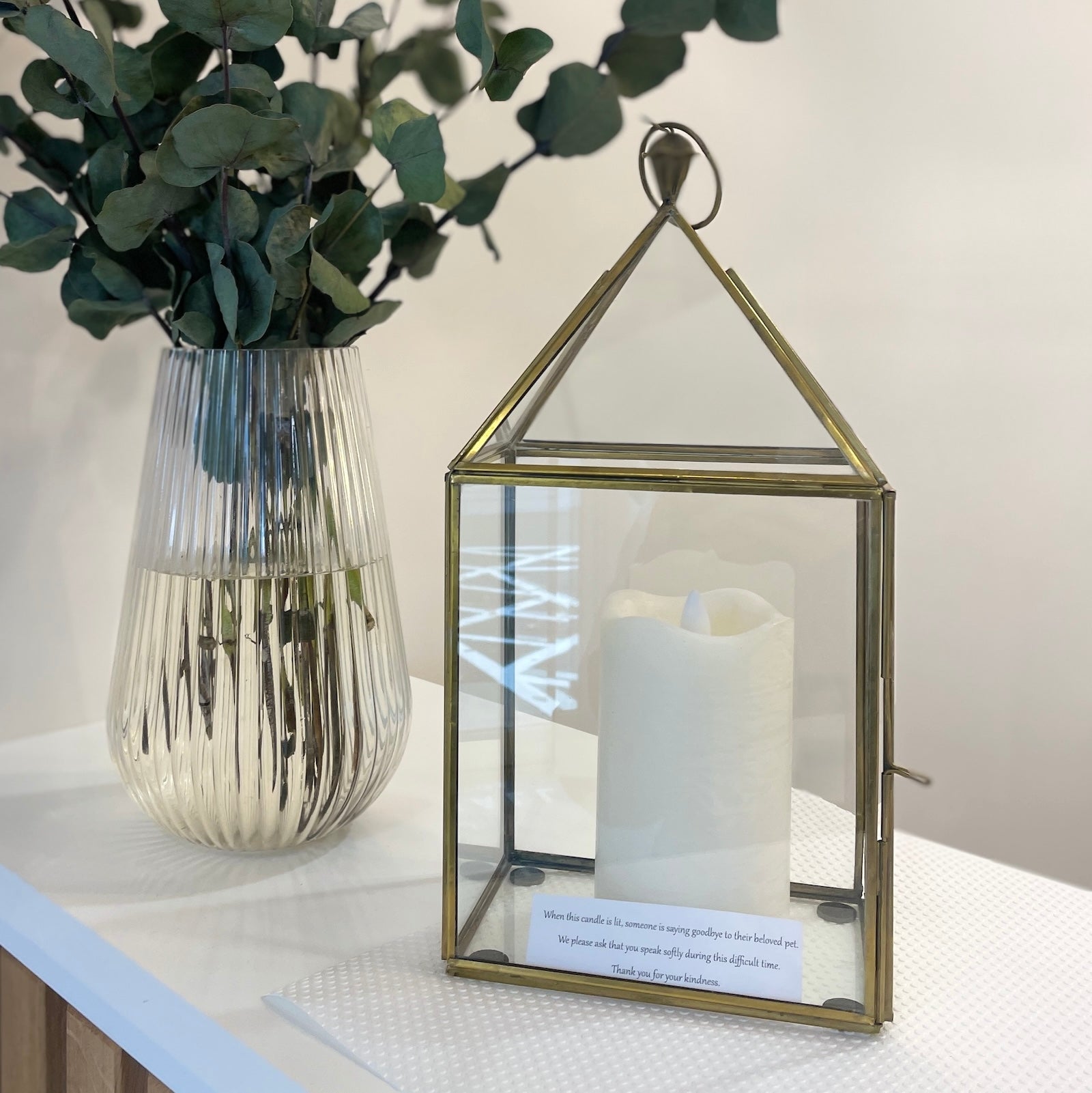 brass candle lantern on shelf with flowers