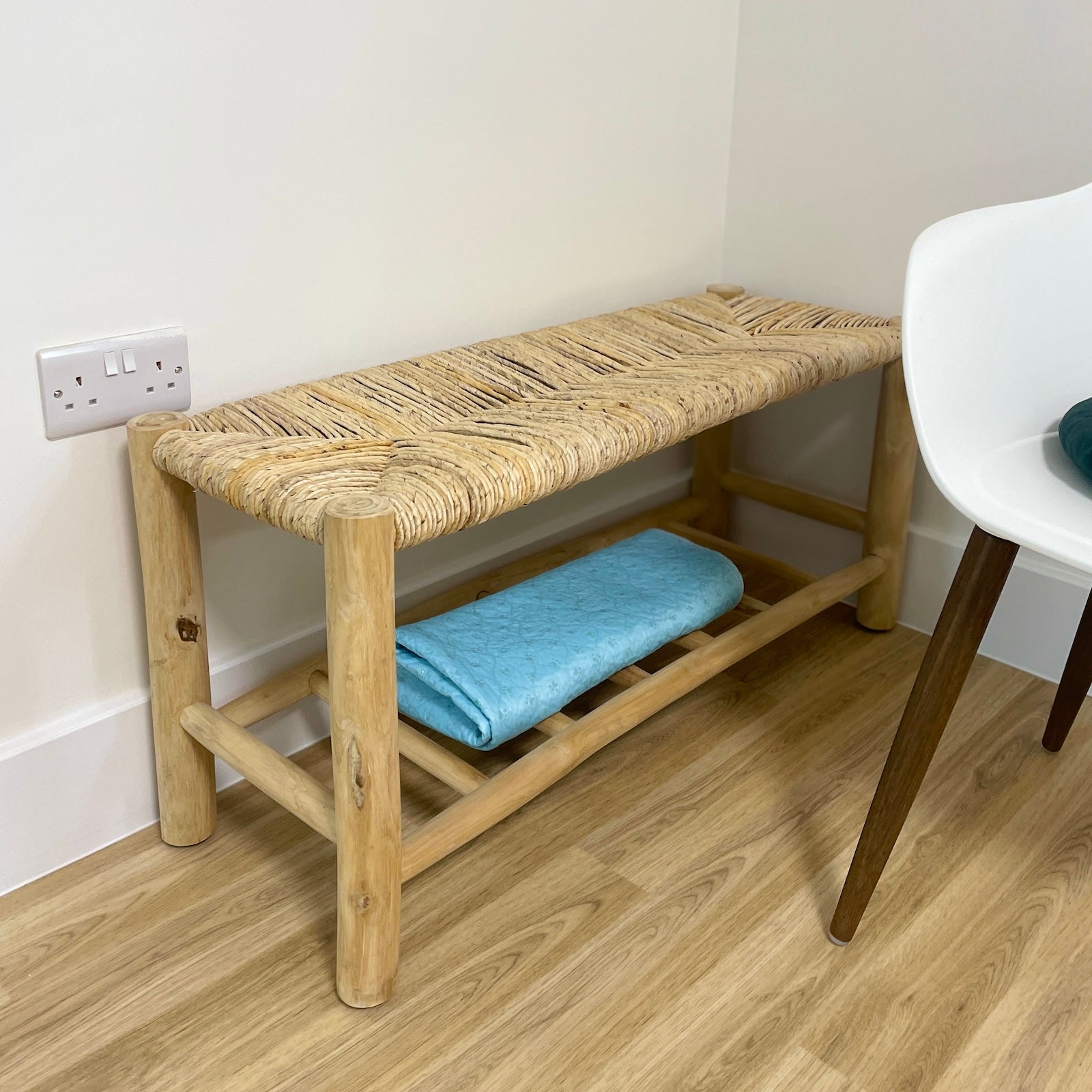 wicker bench with shelf in living room with blanket on shelf