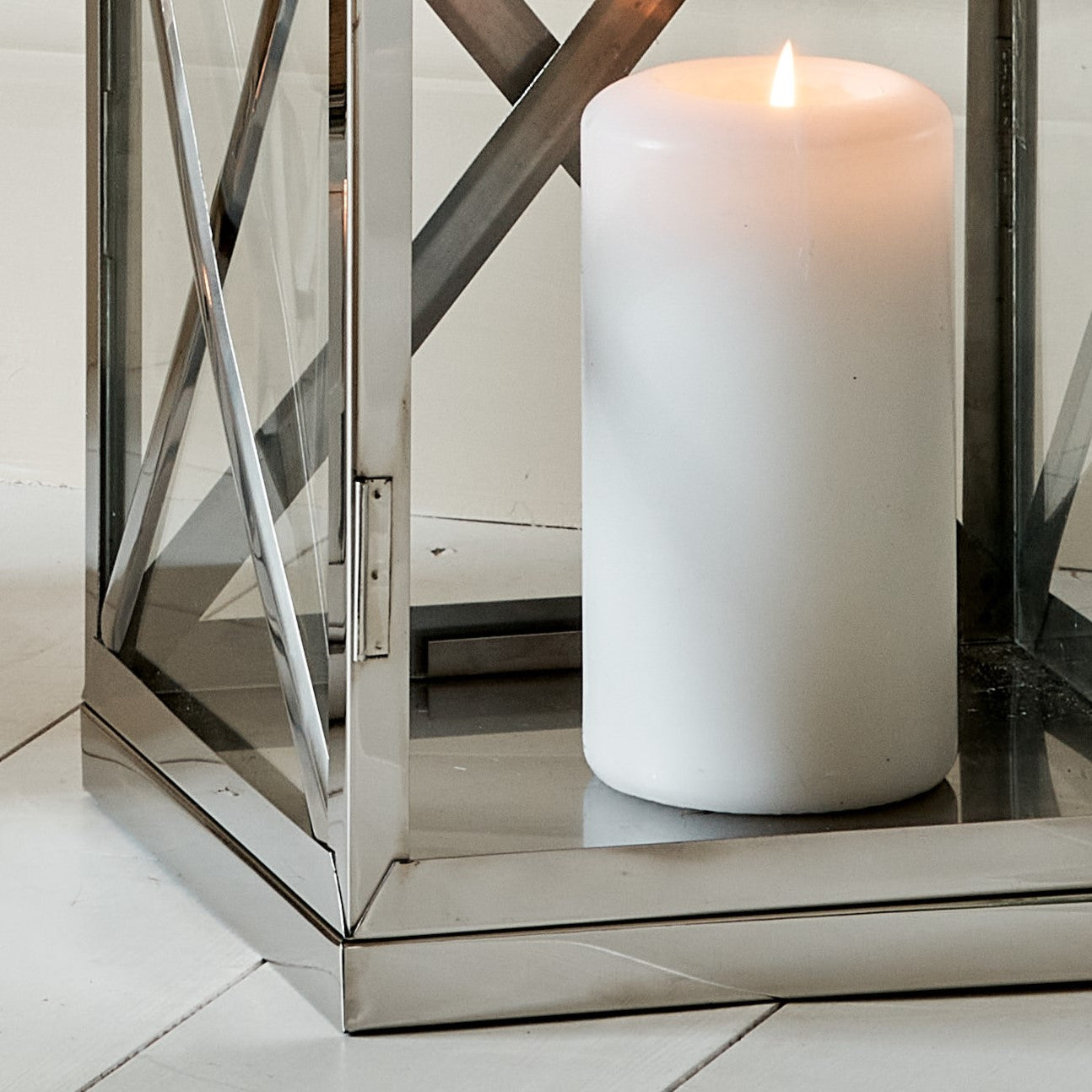Close up of base of Silver and mango wood lantern, with white pillar candle