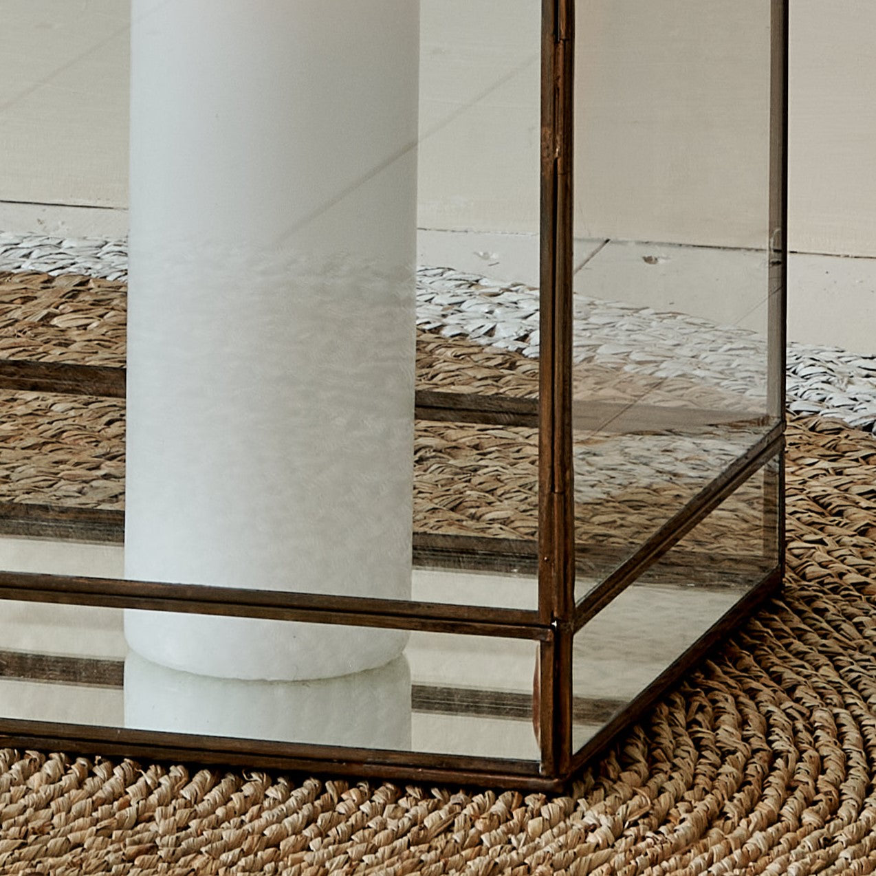 Base of large glass and metal candle lantern square on wicker rug