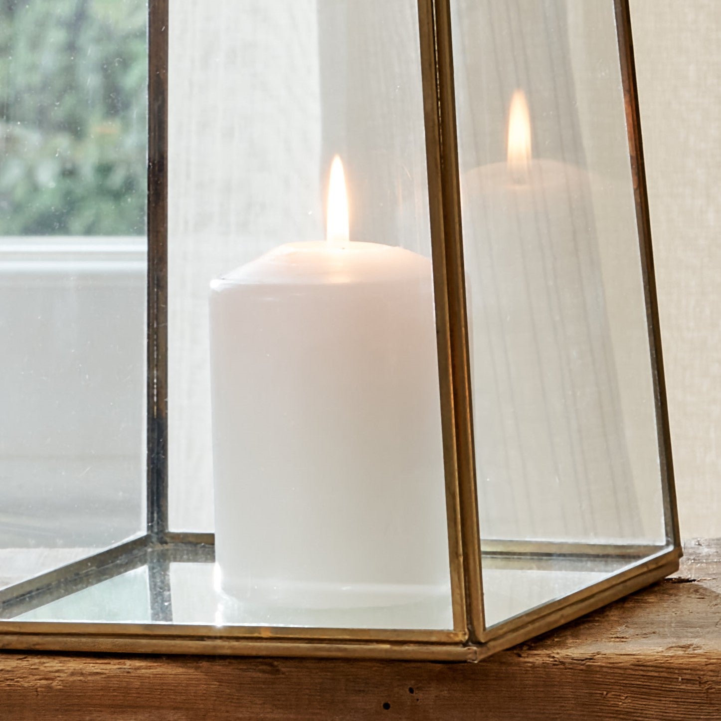 Close up of base of brass pyramid votive lantern on wooden table