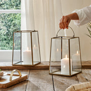 Vintage brass metal lanterns with hand, on wooden table with tray, in front of curtain