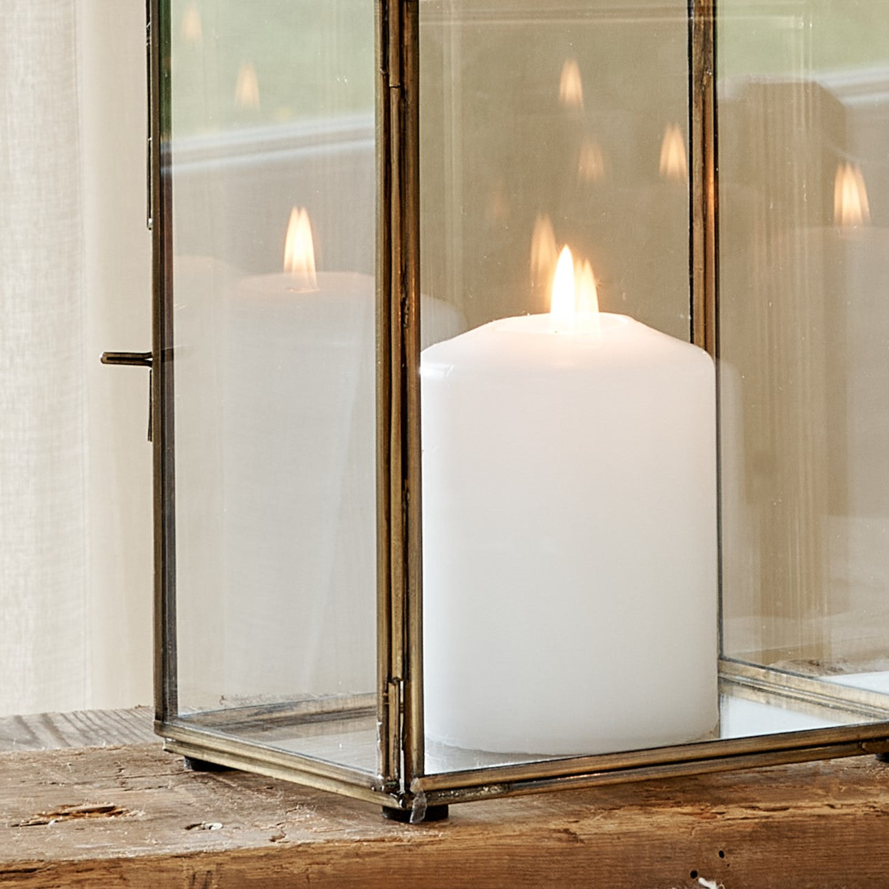 Close up of base of brass candle lantern with white pillar candle