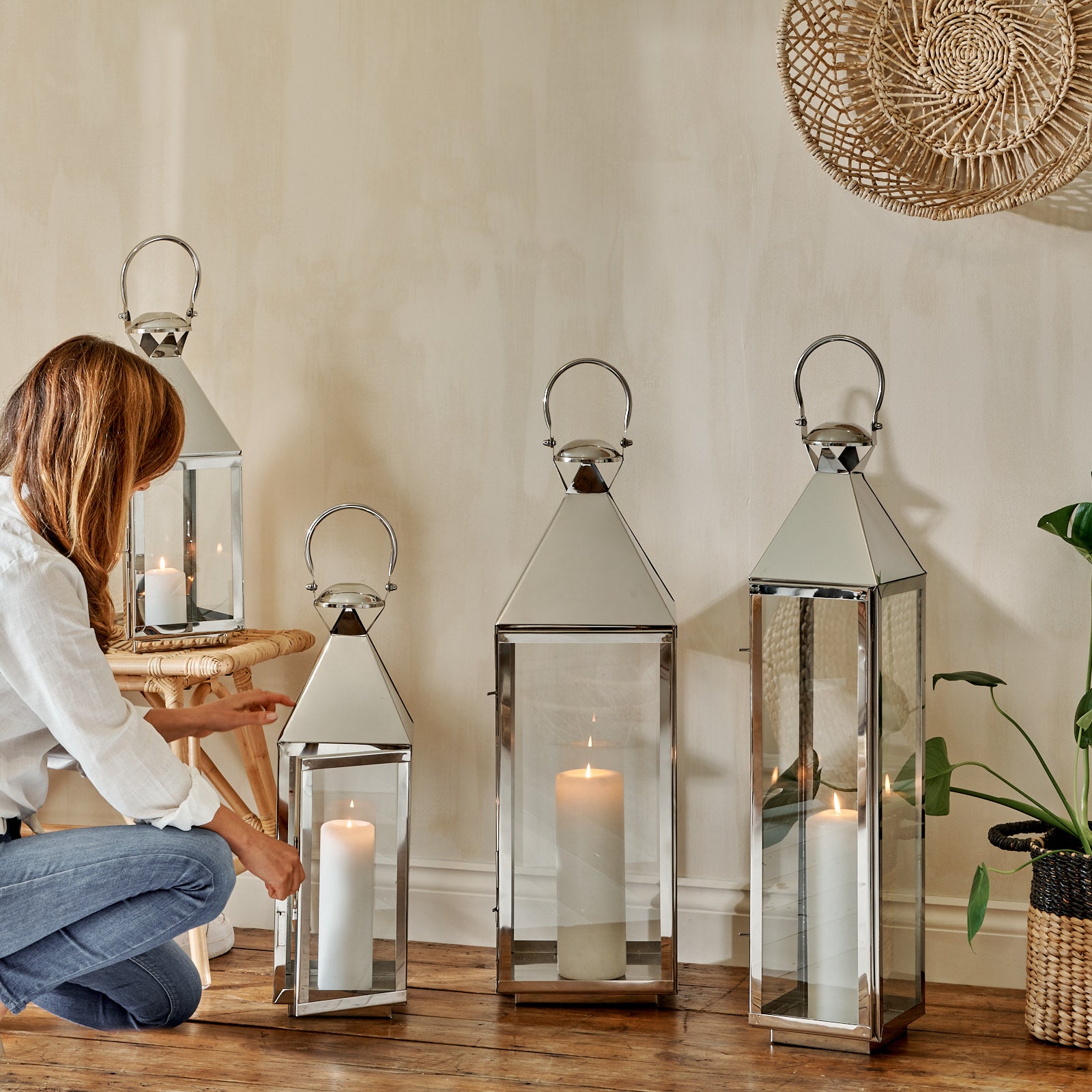 Set of 4 tall metal lanterns on wooden floor with woman opening door
