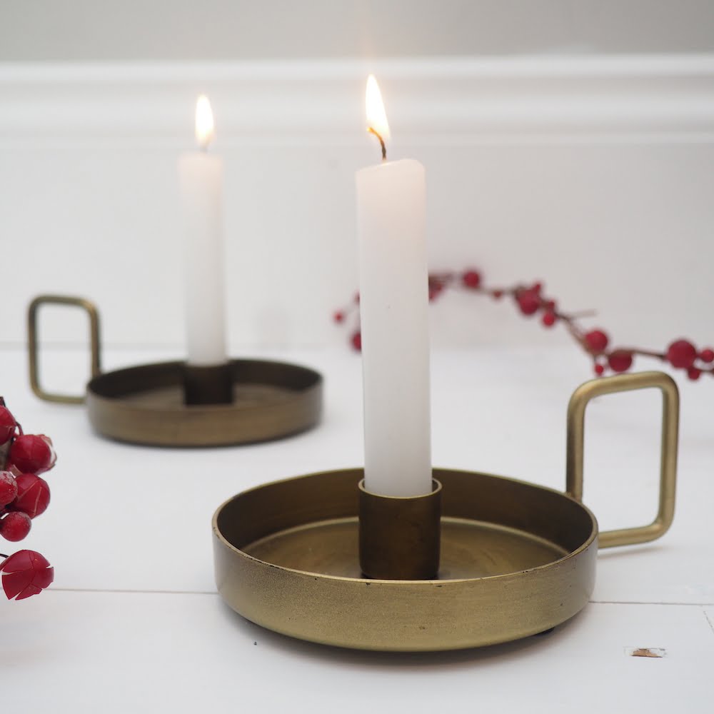 Gold chamberstick candleholder on white surface with berries. Brass antique Victorian chamberstick