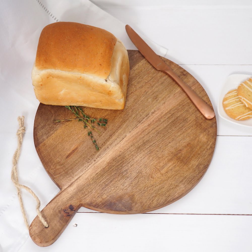 Round wooden chopping board on white wooden table