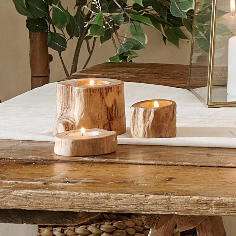 Set of 3 wooden tealight holders on cotton runner one wooden table with plant behind