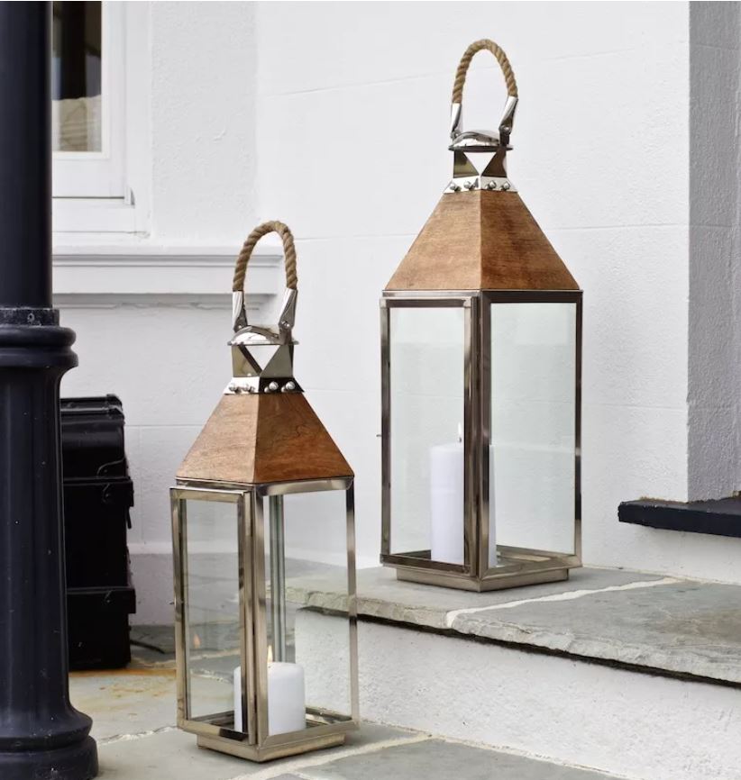 Tall silver candle lantern on front steps of house