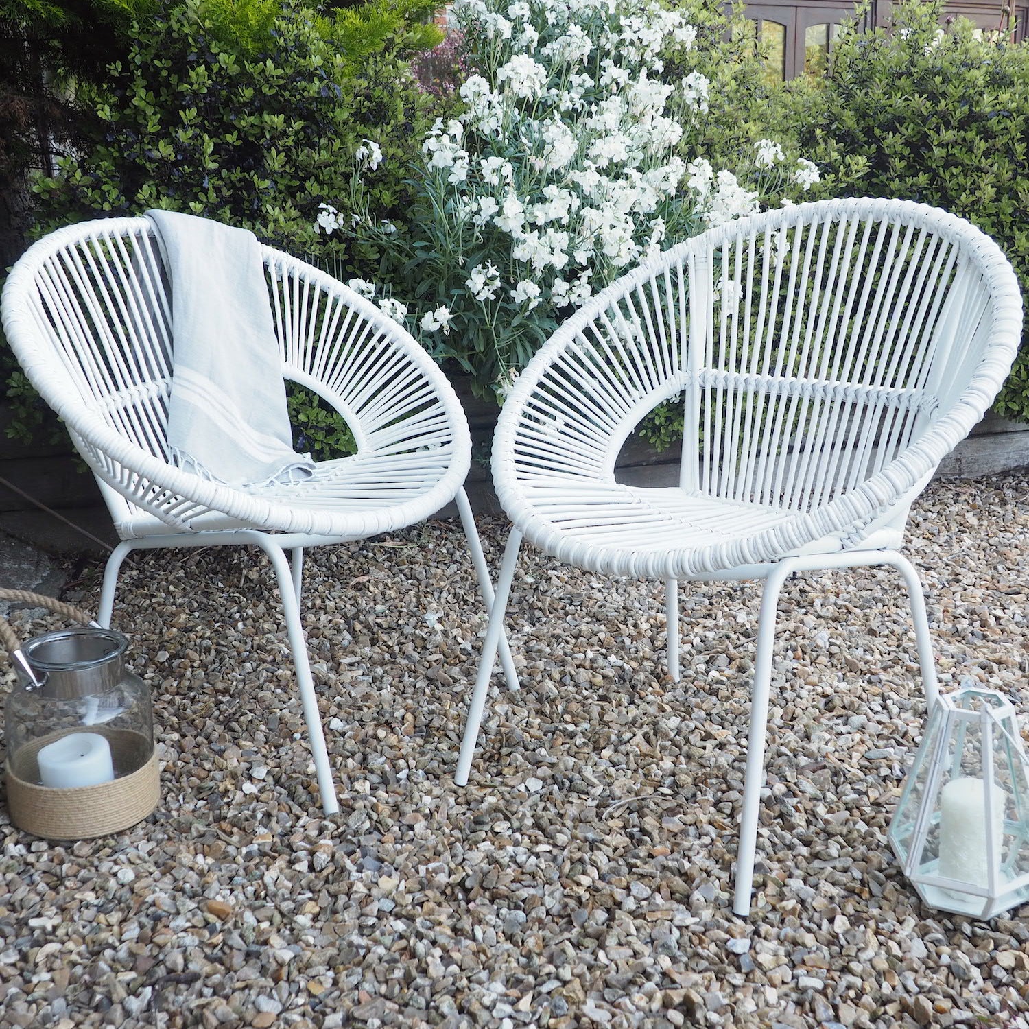 2 white tub chair bamboo on gravel in from of flowering bushes