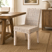 White wash wicker dining chair in a dining room next to a table
