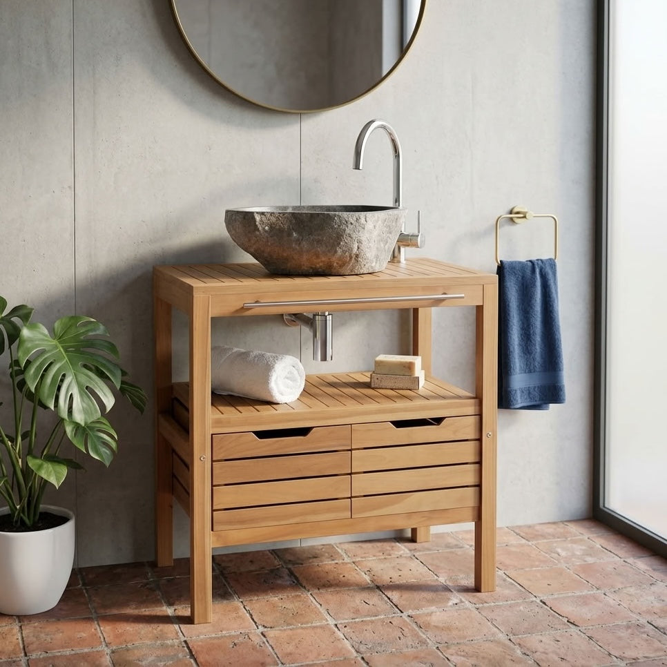 A light teak wood bathroom vanity cabinet with a slatted top and drawers, styled with a stone vessel sink, round mirror, potted plant in a bathroom setting.