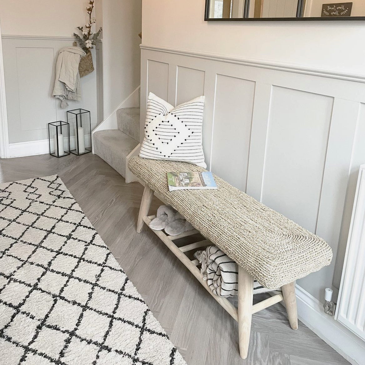 Seagrass wicker bench in hallway on wooden floor next to rug