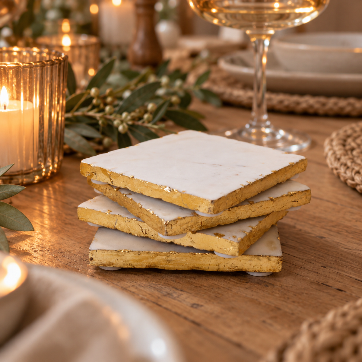 white and gold edged marble drink coasters on a festive dinner table with candlelight and a cocktail glass