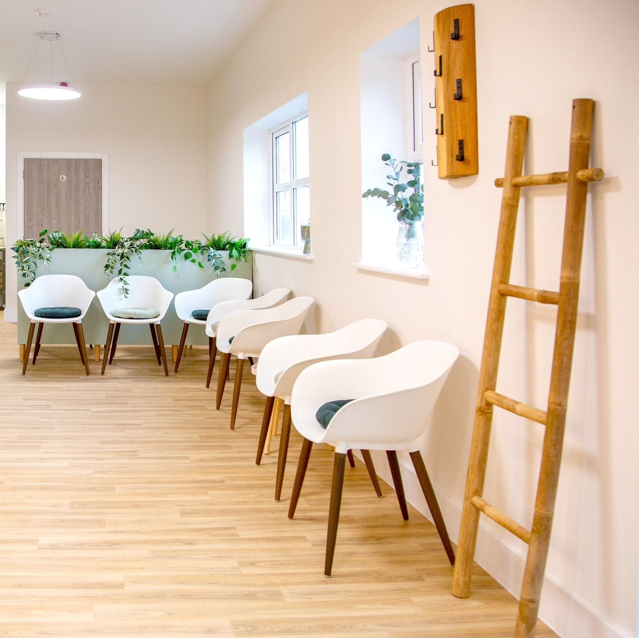waiting room with white chairs, bamboo ladder and wooden floor