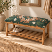 A wooden hallway bench with a shelf, and a patterned kilim green and beige seat, styled in a home entryway with shoes on the slatted shelf.