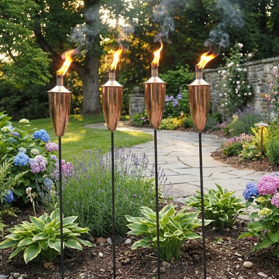 four copper garden oil torches burning in landscaped garden
