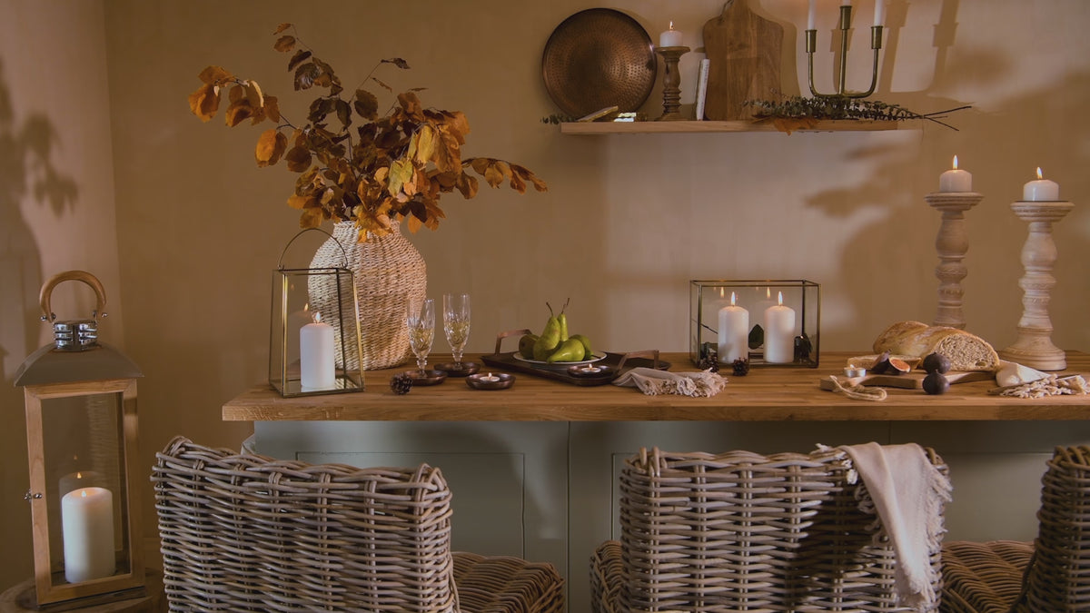 Load video: a cosy christmas and autumnal kitchen island setting with girl moving a wicker kitchen stool and lighting candles