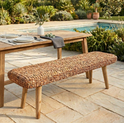 wicker bench in the garden at a dinner table by poolside