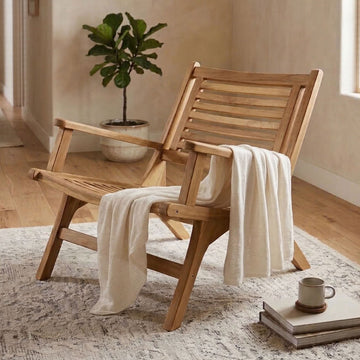 wooden arm chair with a linen throw in a living room on a patterned rug