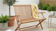 garden bench on patio with plants and wicker rug