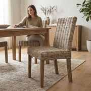 rattan dining chair at dining table with women reading a magazine, on a patterned rug